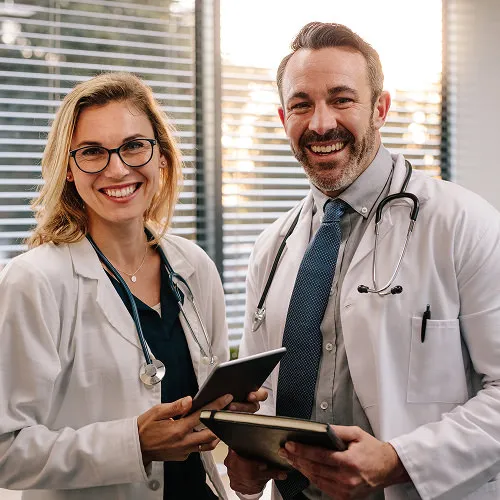 Smiling doctors standing together with tablet