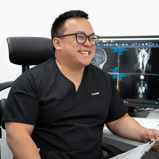 Dr. Grace at desk reviewing MRI scans on monitors