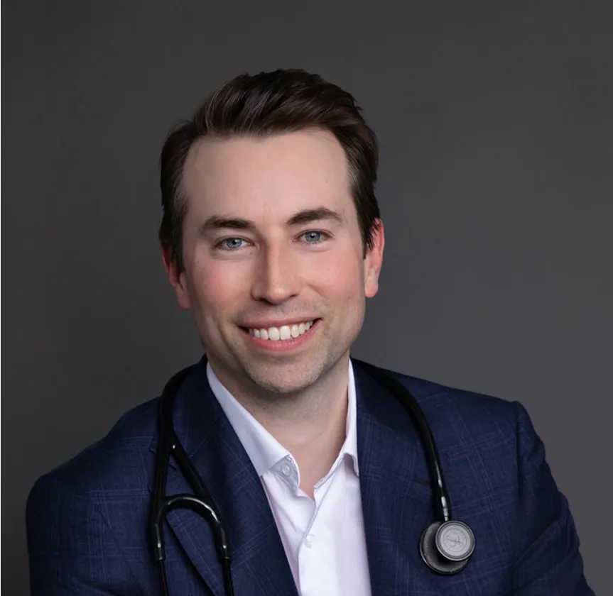 Male doctor in dark blazer with stethoscope smiling

